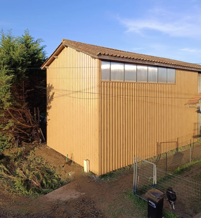 Bâtiment moderne en bois avec bardage vertical, toit à deux pans en tuiles terre cuite