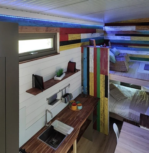 Intérieur compact d'une tiny house moderne avec couchettes superposées colorées en bois peint multicolore