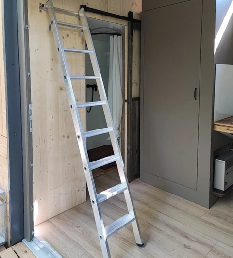 Intérieur en construction avec échelle aluminium déployée contre mur en bois brut