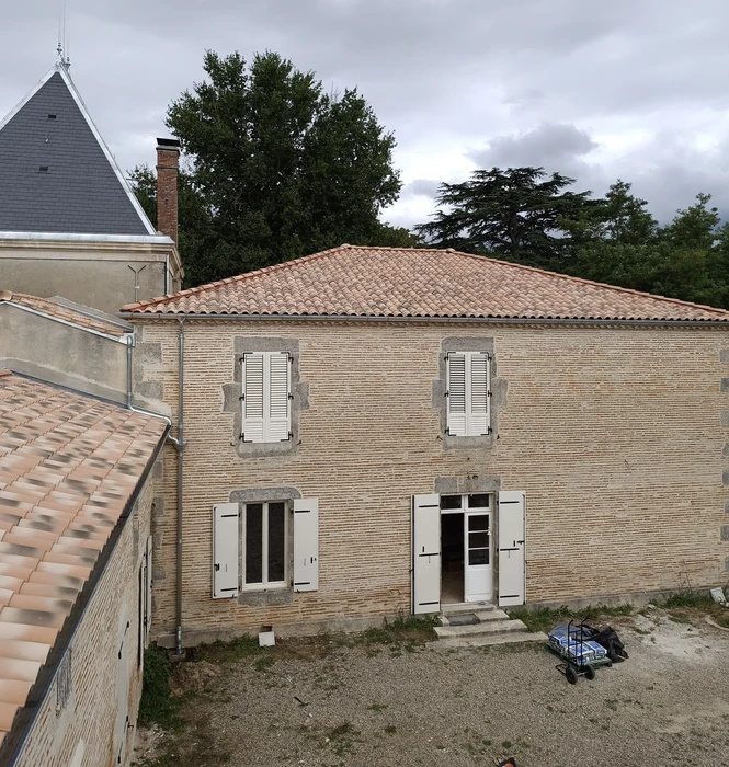 Chantier de rénovation d'une maison en briques avec toiture en tuiles canal