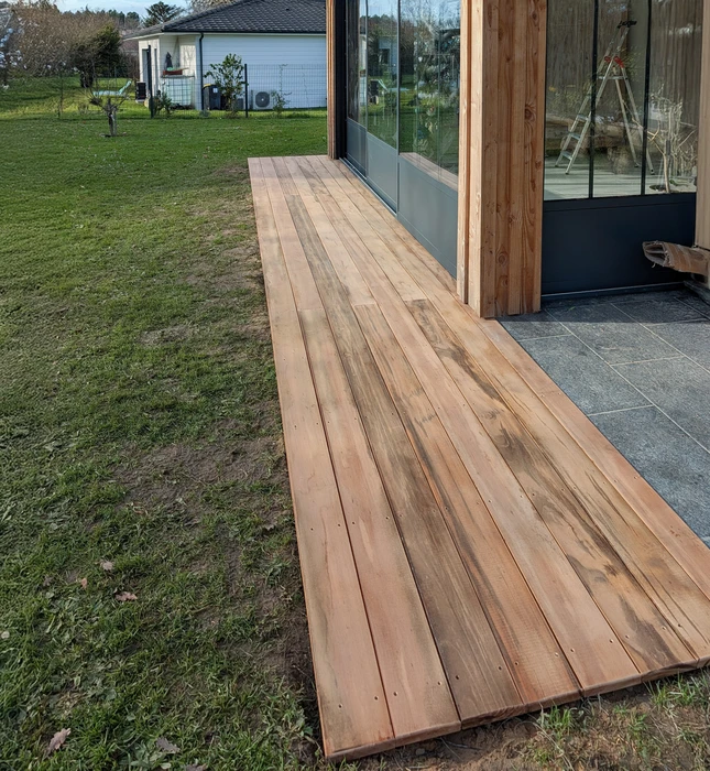 Façade extérieure de bâtiment en cours de rénovation avec bardage bois naturel vertical moderne contrastant avec ancienne section en bois peint gris-bleu vieilli