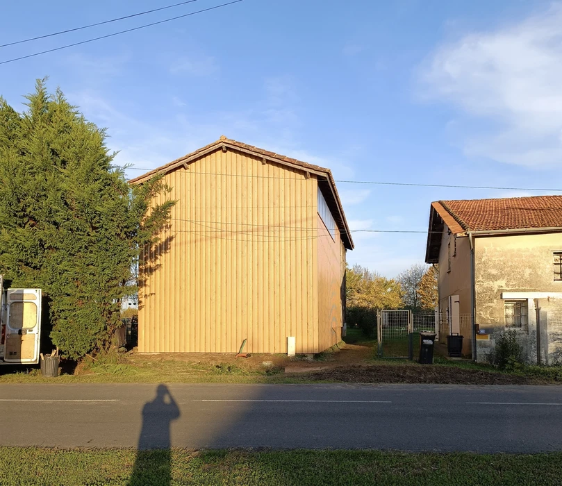 Intérieur de combles aménagés avec charpente en bois apparente, lambris vertical en pin naturel et plafond blanc