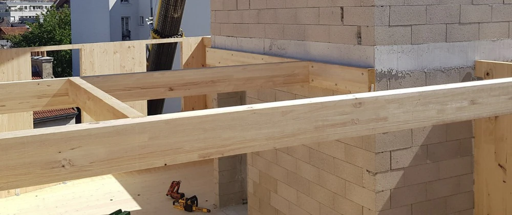 Chantier de construction intérieure en cours, combles aménagés avec charpente bois apparente