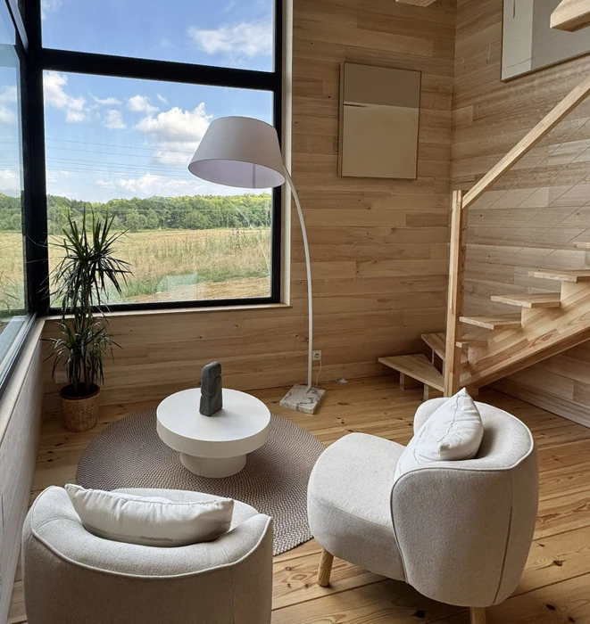 Couloir intérieur d'habitation avec porte d'entrée en bois naturel équipée d'une poignée noire et document affiché