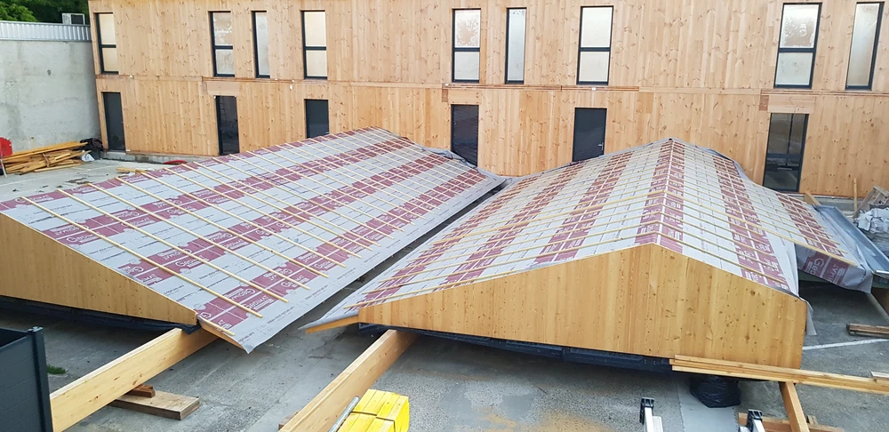 Bâtiment moderne en bois avec bardage vertical, toit à deux pans en tuiles terre cuite