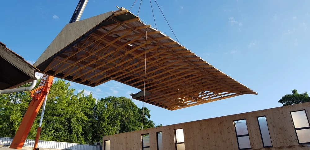 Bâtiment moderne en bois avec bardage vertical, toit à deux pans en tuiles terre cuite