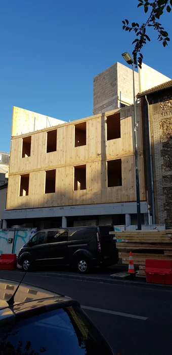 Bâtiment moderne en bois avec bardage vertical, toit à deux pans en tuiles terre cuite