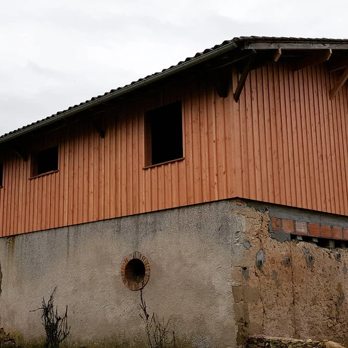 Bâtiment moderne en bois avec bardage vertical, toit à deux pans en tuiles terre cuite